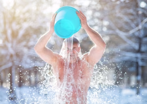 Man taking a cold shower wim hof style outside in a snowy forest